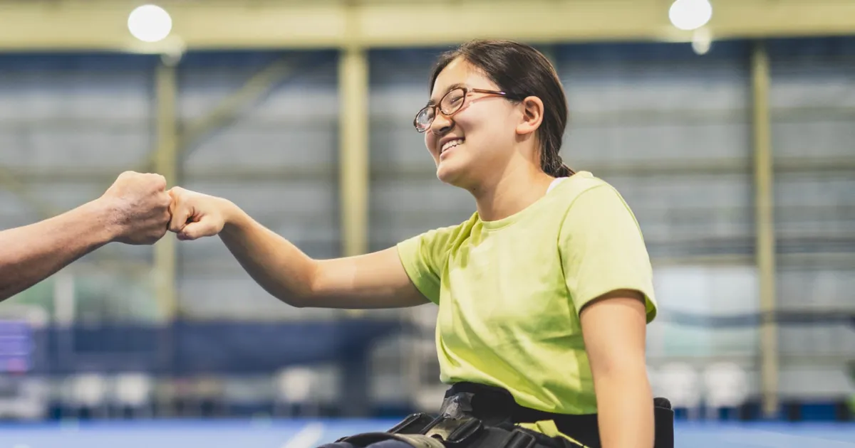 A young wheelchair user smiling in a sports hall